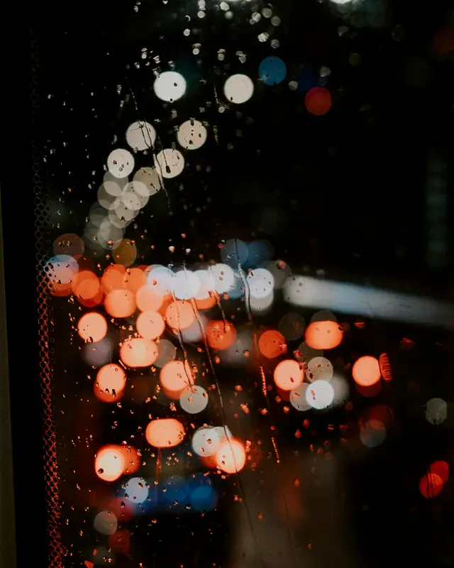 窗玻璃上的雨珠，後面的街燈散成一團團光